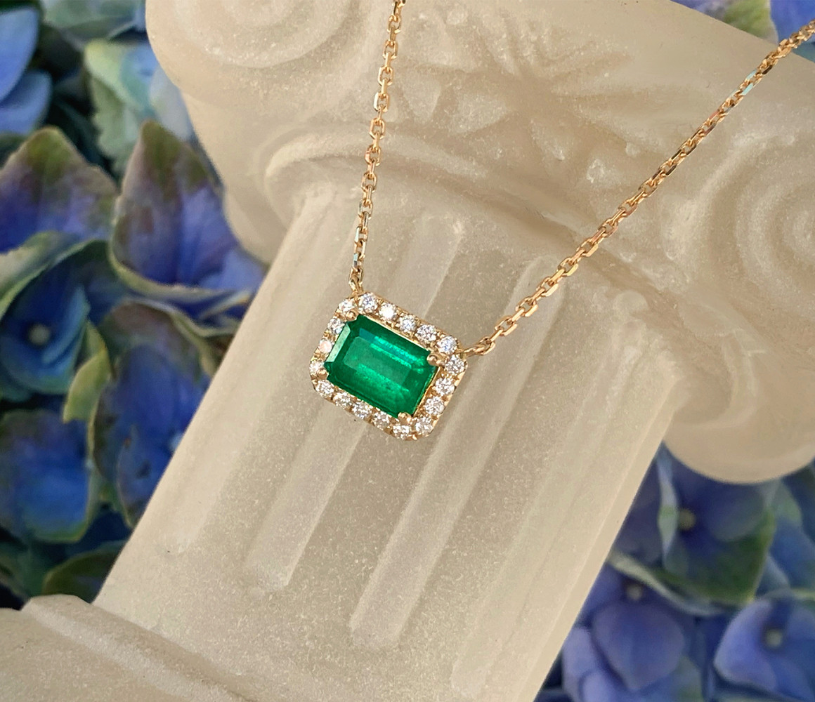 Goldene Halskette mit Smaragd und Diamanten, detailreich, elegant aufgestellt.