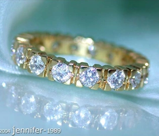 Goldener Diamant Memory Ring mit funkelnden Steinen auf weichem Stoff, Detailaufnahme.