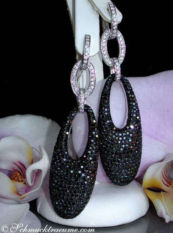 Schwarze Diamanten-Ohrgehänge in Weißgold 585, lang und elegante Form, mit Orchideen im Hintergrund.