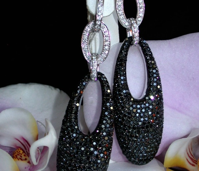 Schwarze Diamanten-Ohrgehänge in Weißgold 585, lang und elegante Form, mit Orchideen im Hintergrund. Schwarze Diamanten-Ohrgehänge in Weißgold 585, lang und elegante Form, mit Orchideen im Hintergrund.