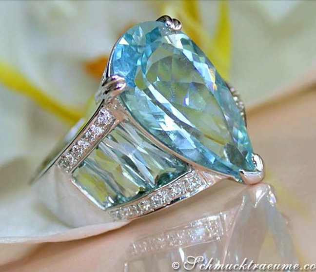 Weißgold-Aquamarin-Ring mit Diamanten auf Blütenhintergrund Weißgold-Aquamarin-Ring mit Diamanten auf Blütenhintergrund