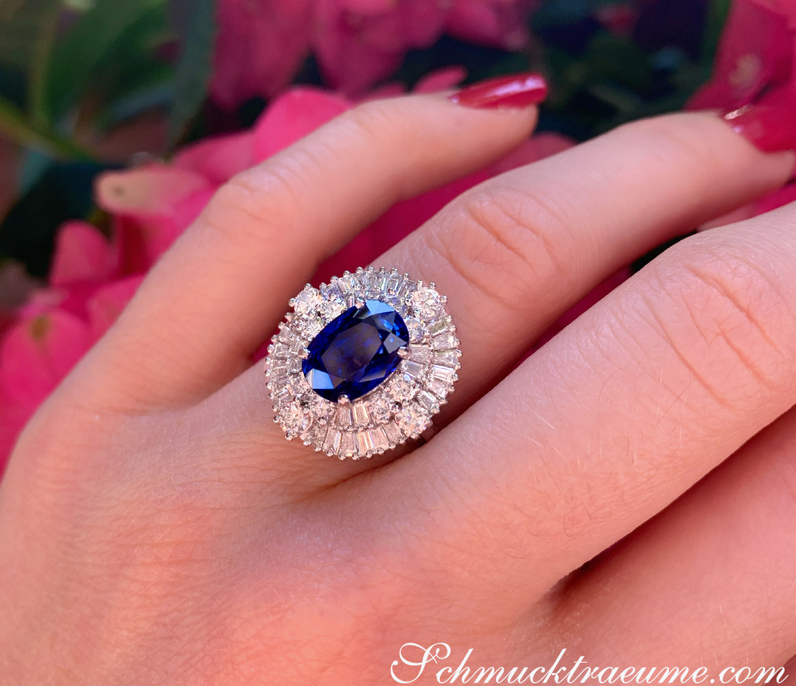 Weißgold-Ring mit blauem Saphir und Diamanten, Detailaufnahme, im Hintergrund Blüten.