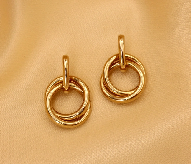 Gelbgold 585 Ohrringe mit verschränkten Ringen auf samtigem Hintergrund Gelbgold 585 Ohrringe mit verschränkten Ringen auf samtigem Hintergrund