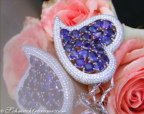 Herzformiger Ceylon-Saphir-Anhänger mit Brillanten, Detailaufnahme, weißes Gold, Rosen im Hintergrund.