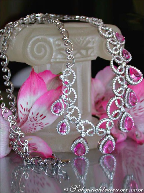 Luxuriöses Pink Saphir Collier mit Brillanten, detailreich, elegant, auf weißem Säulenpodest mit Blütenhintergrund.