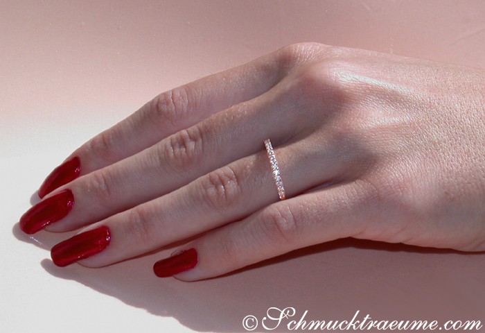 Zarte Diamantring-Verzierung auf Hand mit roten Nägeln