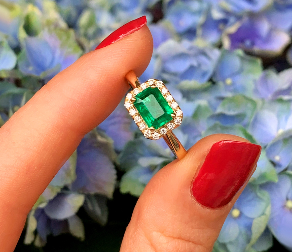 Smaragd-Ring mit Brillanten in Gelbgold 585, detailreich, auf Blütenhintergrund.