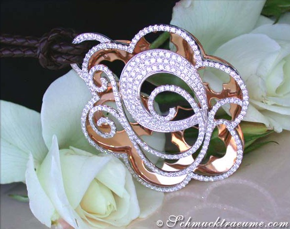 Floraler Brillanten-Anhänger auf Lederkordel, umgeben von Rosenblüten