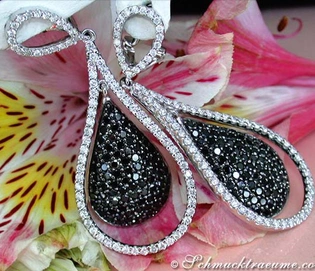 Schwarz-weiße Diamant-Ohrhänger mit Blüten im Hintergrund