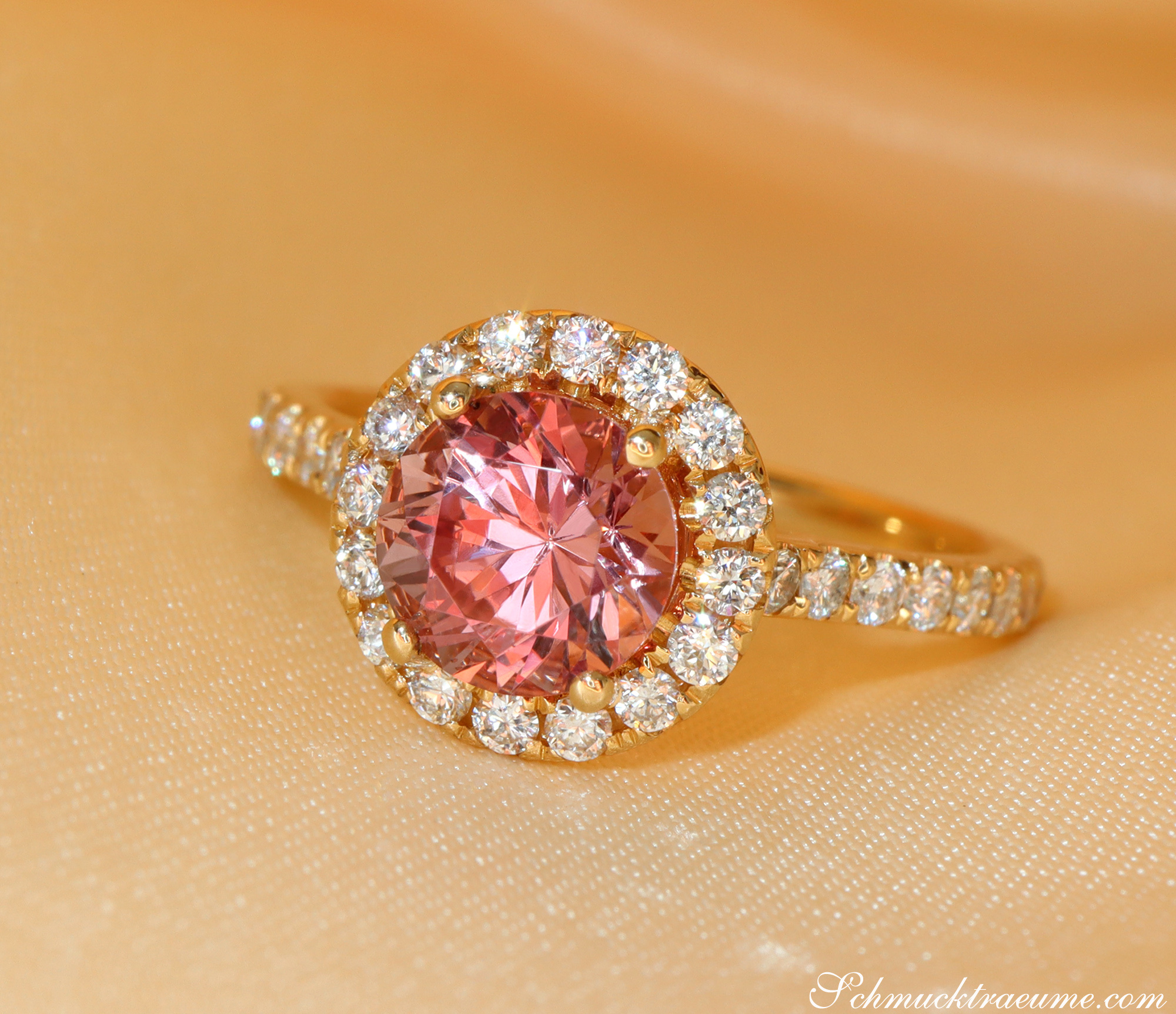 Goldener Ring mit rosa Granat und Diamant-Halo, detailreich, elegant.