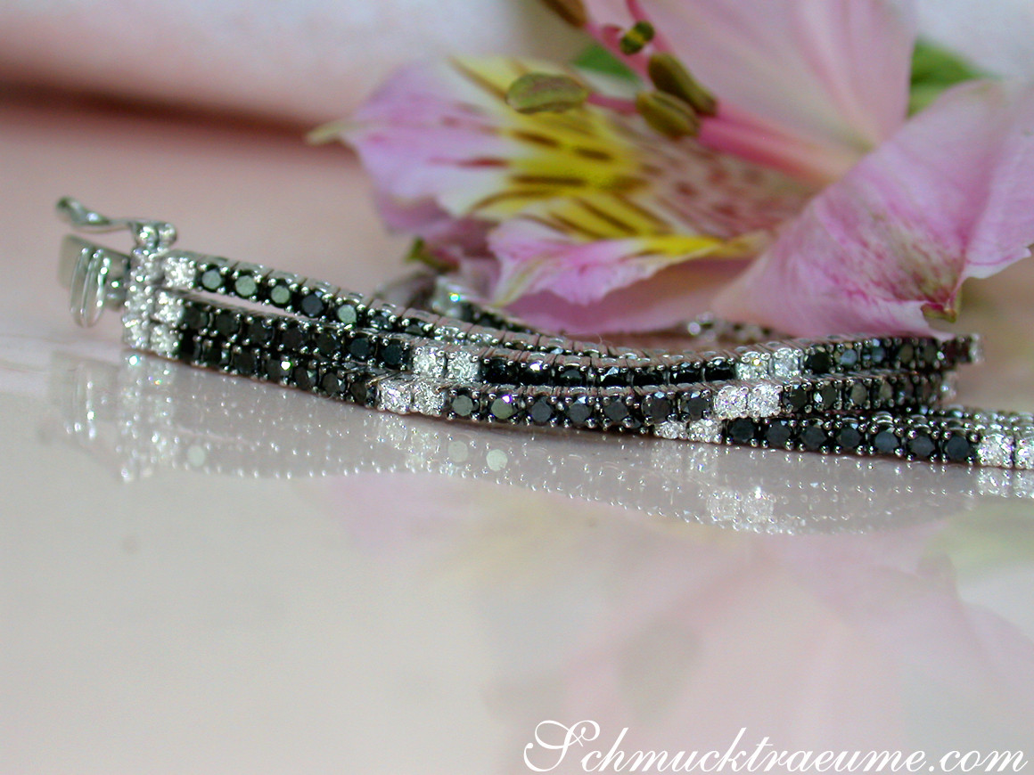 Schwarz-weiß-diamantiertes Tennisarmband, detailreich, auf glänzender Oberfläche, Blüte im Hintergrund.