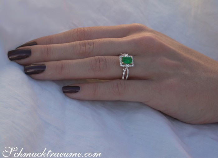 Smaragd-Ring mit Brillanten auf Hand mit dunkler Nagellackfarbe