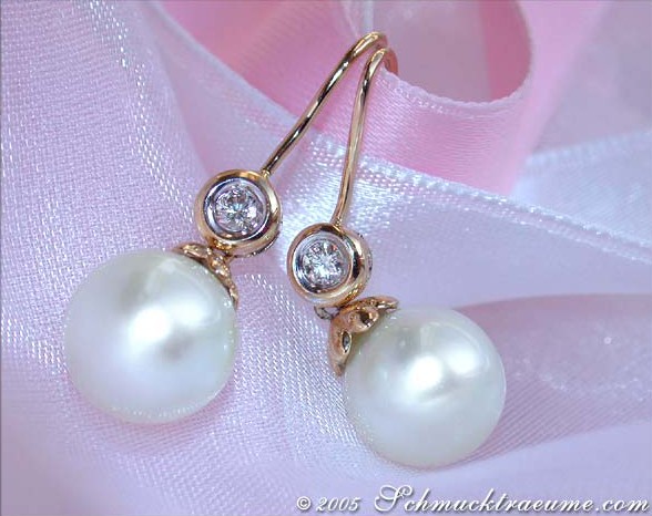 Gelbgold-Ohrhänger mit großen Perlen und Brillanten auf rosa Seide.