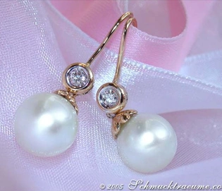 Gelbgold-Ohrhänger mit großen Perlen und Brillanten auf rosa Seide.