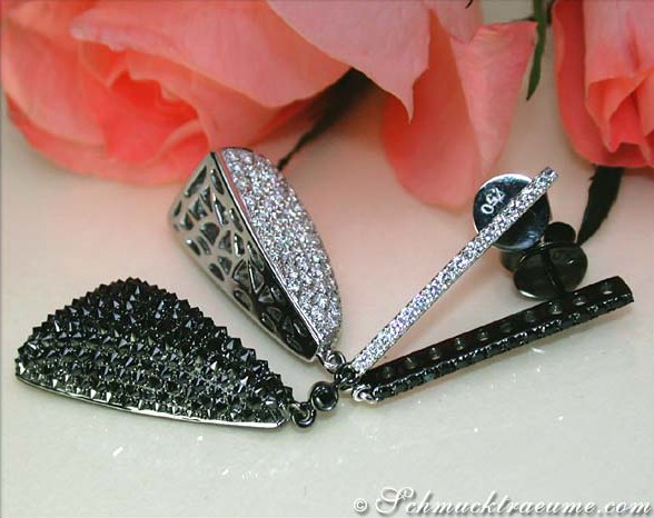 Schwarze Diamant-Ohrgehänge mit weißem Gold, Detailaufnahme, rosa Blüte im Hintergrund.