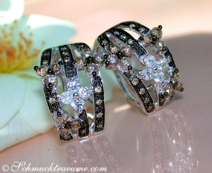 Floraler Ohrstecker aus Weißgold 585, verziert mit naturbraunen und weißen Diamanten, auf Blütenblatt-Hintergrund.