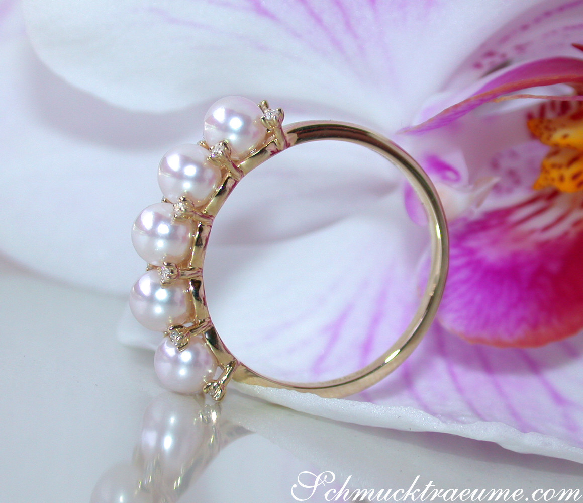Gelbgoldring mit 9 Akoya-Pearlen und Diamanten, Detailaufnahme, Orchidee im Hintergrund