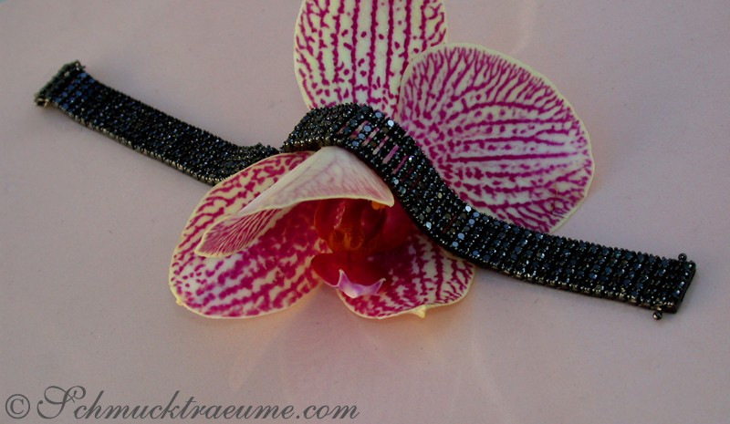 Schwarzrhodiniertes Armband mit 410 Diamanten, Orchideenblüte im Hintergrund
