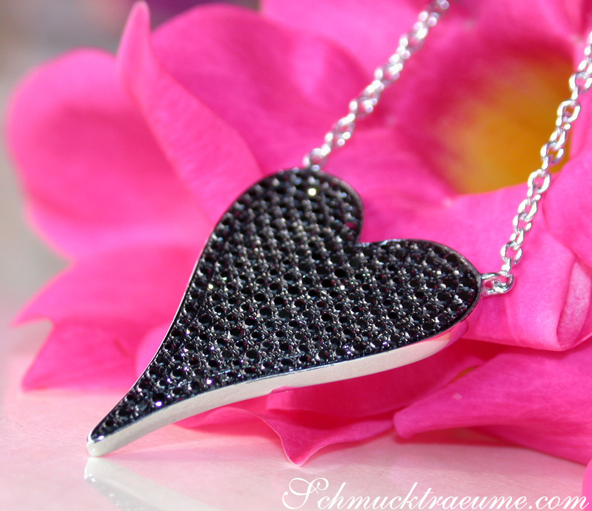 Schwarze Diamanten Herzanhänger auf Silberkette vor Blüte