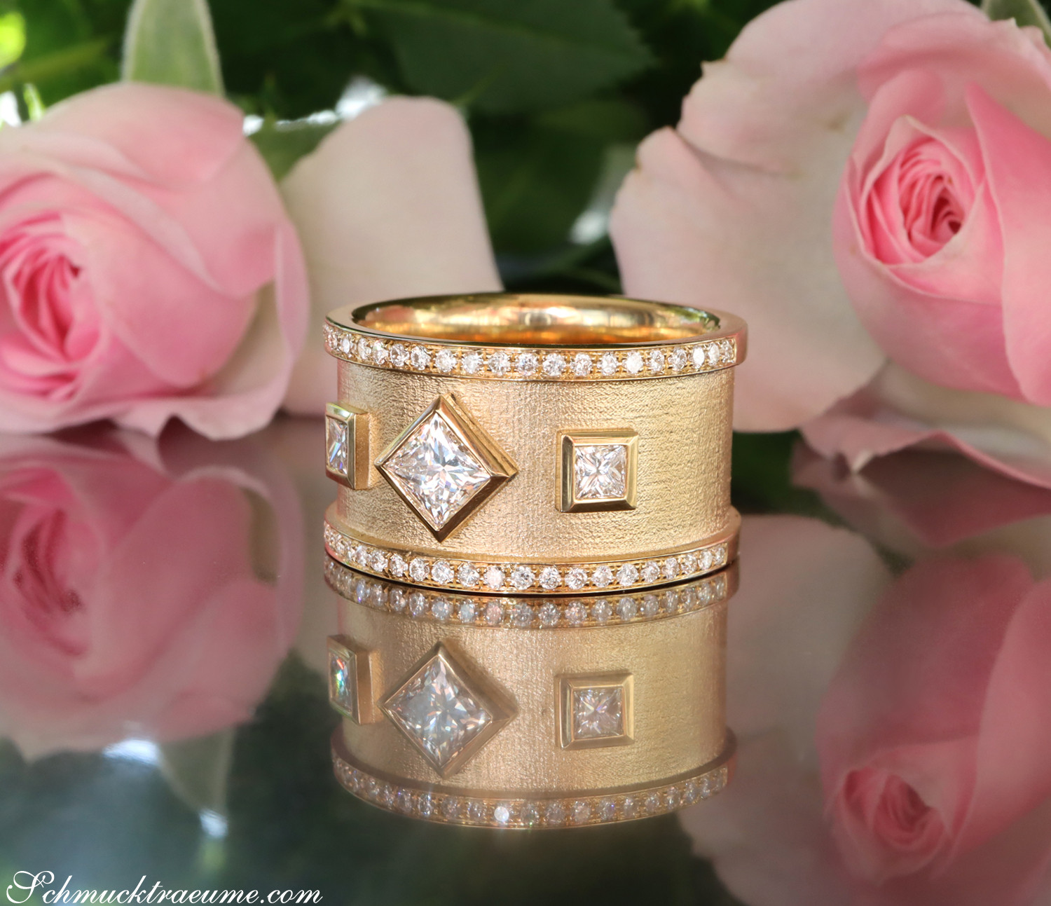 Goldener Diamant-Ring mit Prinzessenschliff-Diamanten und Diamant-Kranz, umgeben von Rosenblüten.