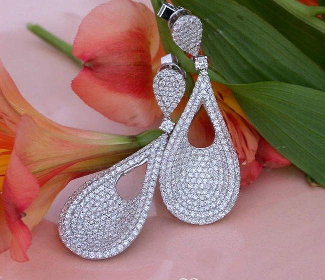 Diamant-Tropfen-Ohrringe in Weißgold, elegant auf Blütenblättern präsentiert Diamant-Tropfen-Ohrringe in Weißgold, elegant auf Blütenblättern präsentiert