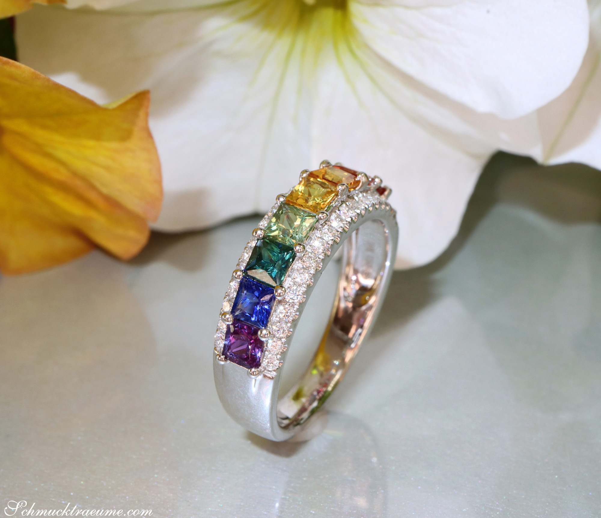 Weißgold-Ring mit Regenbogen Saphiren und Brillanten, Blume im Hintergrund