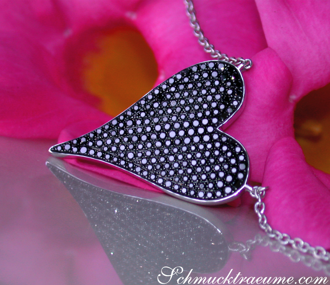 Schwarz-diamantener Herzanhänger auf rosafarbenem Blütenblatt, Detailaufnahme.