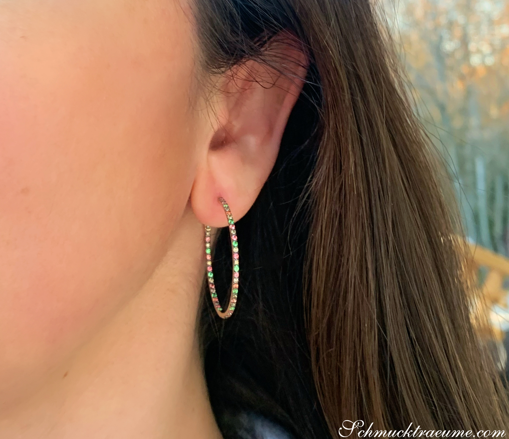 Zarte Creolen mit braunen Diamanten, orangen Saphiren & Tsavorite, detailnah auf dem Ohr getragen.