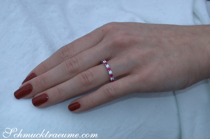 Weißgold-Ring mit Rubinen und Diamanten auf Hand mit lackierten Nägeln