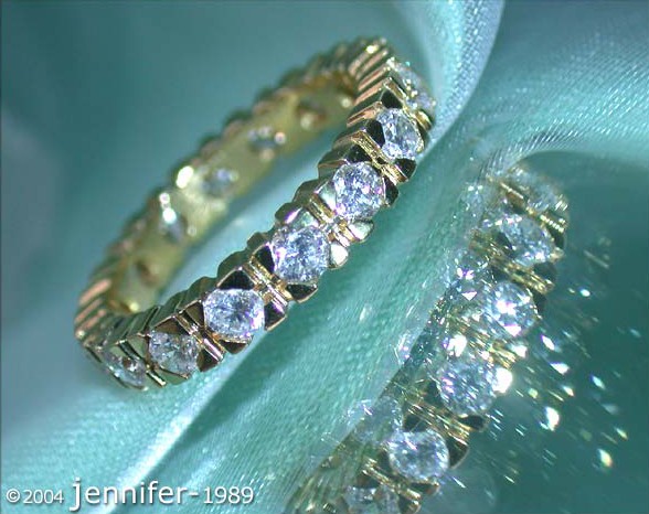 Detailansicht des Gelbgold-Diamant-Memory-Rings mit Brillanten auf grünem Stoff.
