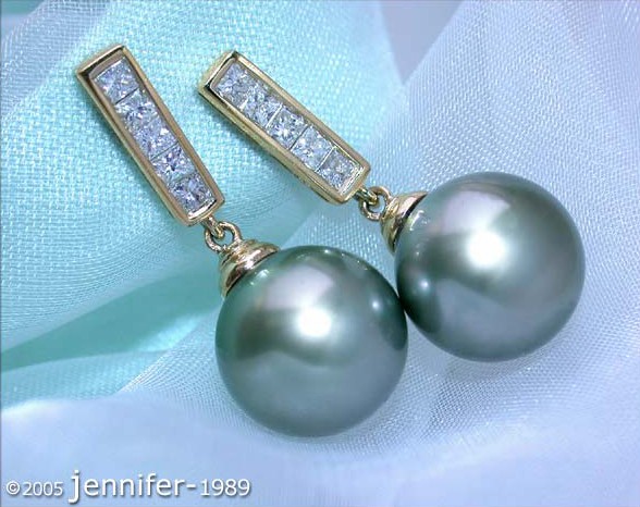 Gelbgold-750-Ohrstecker mit Tahitiperlen und Diamanten, detailreich, elegant, auf blauem Stoff liegend.