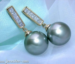 Gelbgold-750-Ohrstecker mit Tahitiperlen und Diamanten, detailreich, elegant, auf blauem Stoff liegend.