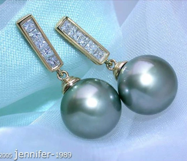 Gelbgold-750-Ohrstecker mit Tahitiperlen und Diamanten, detailreich, elegant, auf blauem Stoff liegend. Gelbgold-750-Ohrstecker mit Tahitiperlen und Diamanten, detailreich, elegant, auf blauem Stoff liegend.