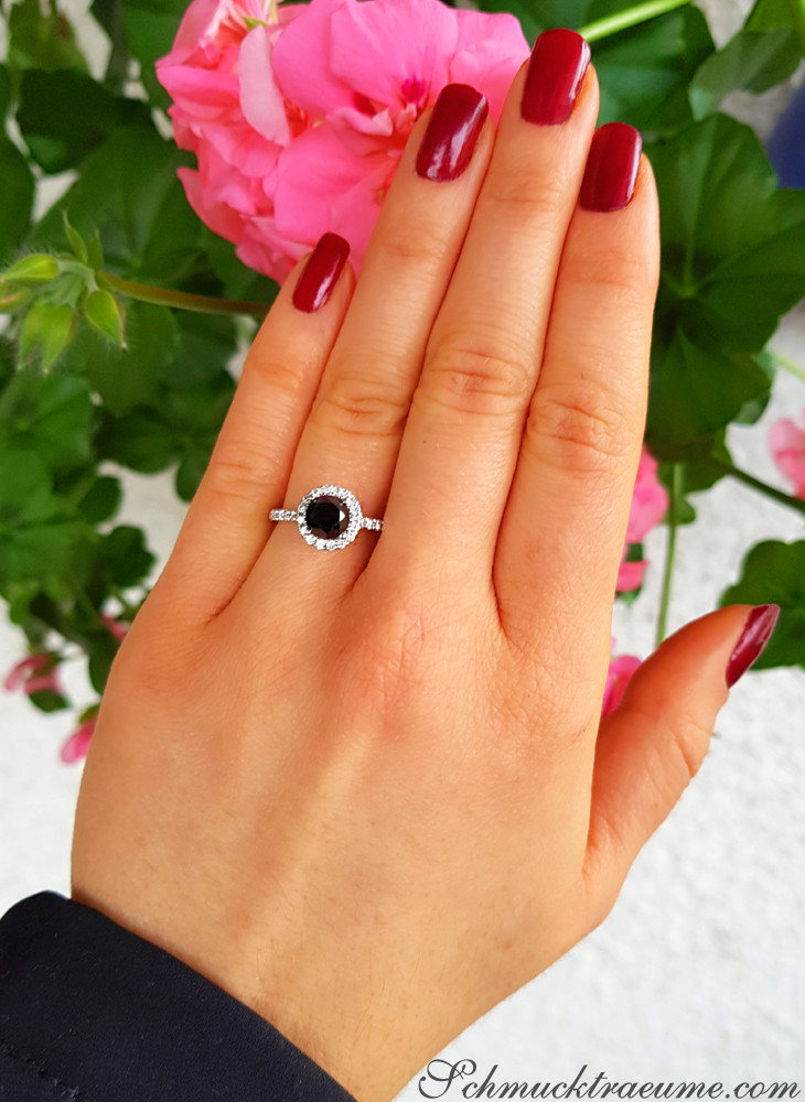 Schwarzer Diamant Solitär Ring mit Halo-Design, Nagelkunst, Blumen im Hintergrund