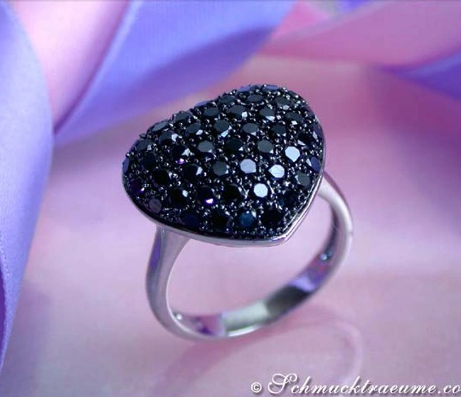 Schwarzer Herzring mit Diamanten auf Silberband, vor lila Seidenband, elegante Ansicht. Schwarzer Herzring mit Diamanten auf Silberband, vor lila Seidenband, elegante Ansicht.