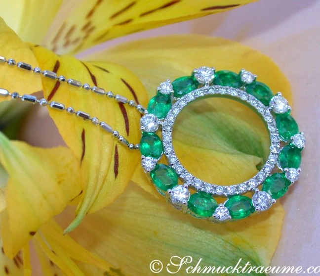 Smaragd-Brillanten-Anhänger auf Kette, gelbe Blume im Hintergrund Smaragd-Brillanten-Anhänger auf Kette, gelbe Blume im Hintergrund