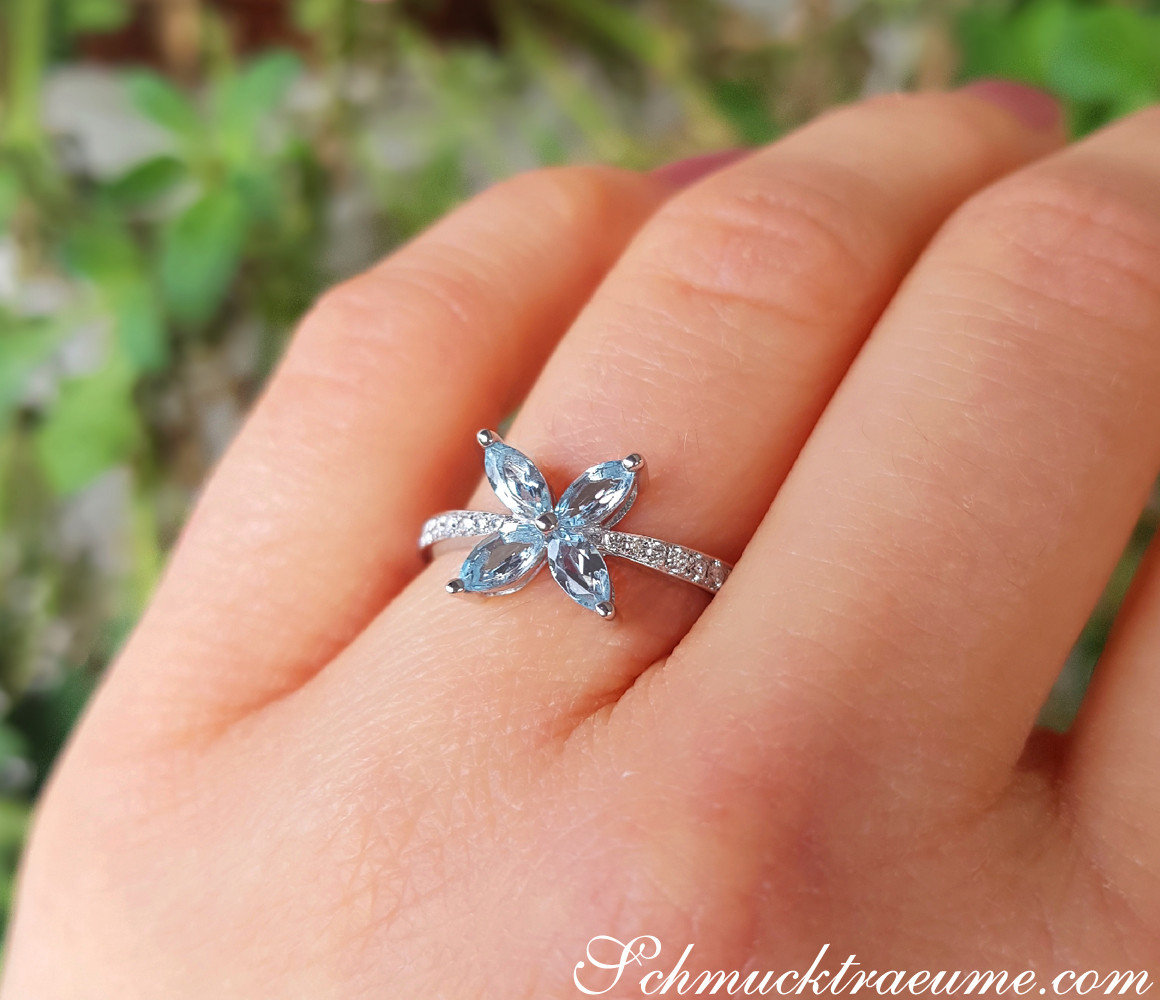 Blütenförmiger Aquamarin-Ring mit Diamanten auf Hand, Natur im Hintergrund