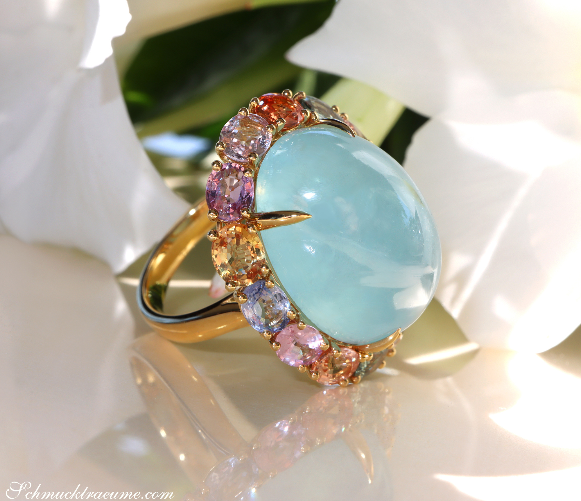 Goldener Milky Aquamarin-Ring mit farbigen Saphiren, Detailaufnahme, Blütenhintergrund.