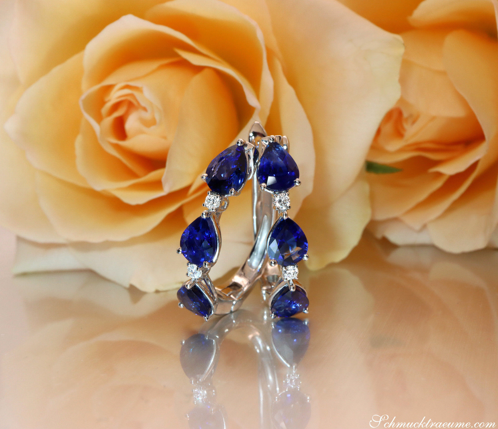 Blumenblüten-Ohrringe mit Saphir-Tropfen und Diamanten, elegant auf Rosenblüte präsentiert