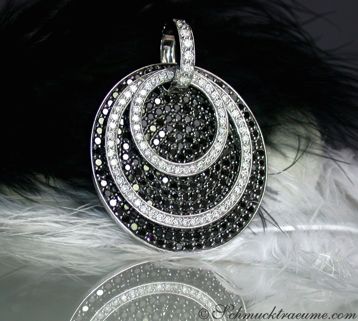 Schwarz-weiß Diamantanhänger mit drei Ringen, Detailaufnahme, auf Federhintergrund.