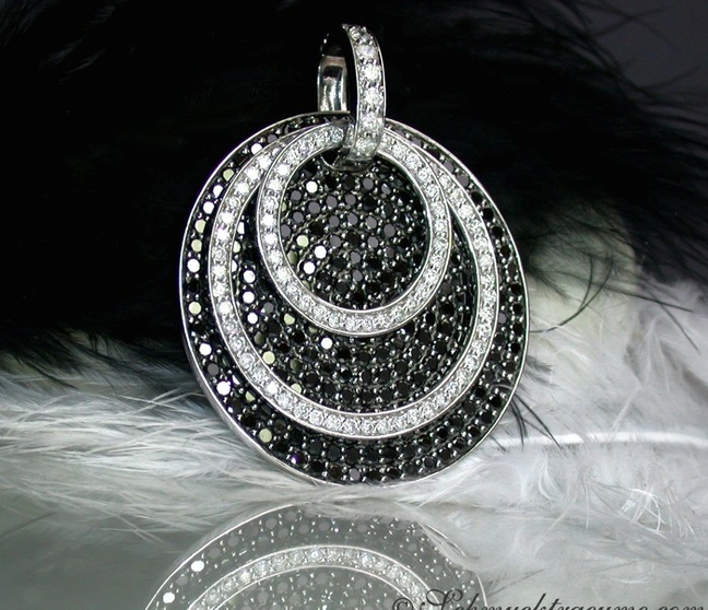 Schwarz-weiß Diamantanhänger mit drei Ringen, Detailaufnahme, auf Federhintergrund. Schwarz-weiß Diamantanhänger mit drei Ringen, Detailaufnahme, auf Federhintergrund.