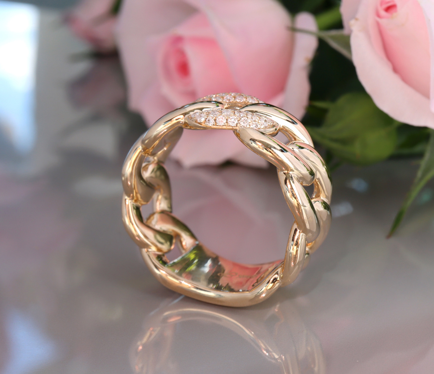 Goldener Panzerkett-Ring mit Brillanten, Detailaufnahme, Rosen im Hintergrund