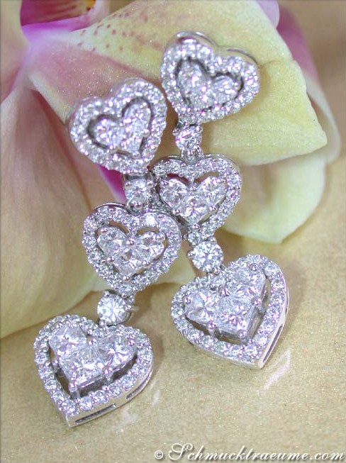 Herzform-Ohrgehänge mit Princess-Diamanten, Detailaufnahme, getragen auf Orchideenblüte.