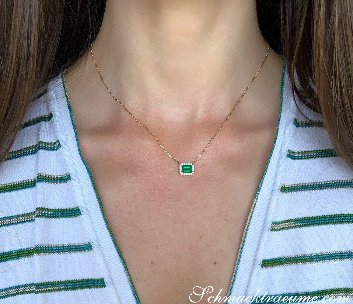 Goldene Halskette mit Smaragd und Brillanten, detailgetreu getragen.