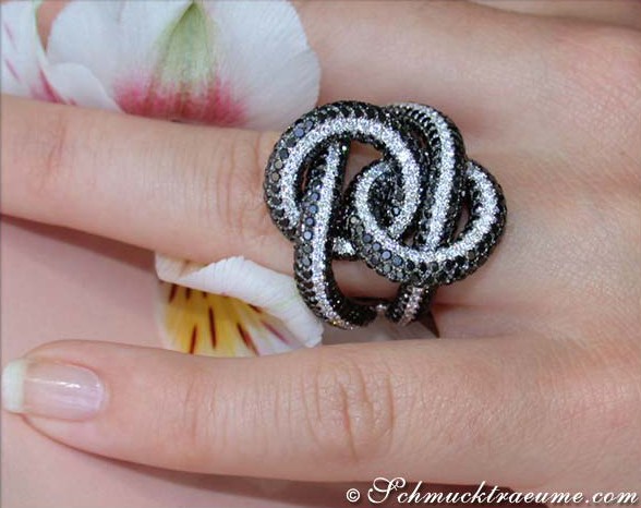 Schwarzer Diamant-Ring auf Hand mit Blume im Hintergrund