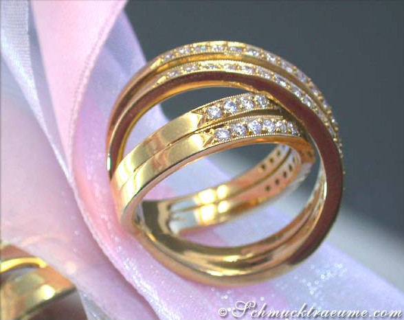 Verzierte Gelbgold-Ringe mit Diamanten auf rosa Seide