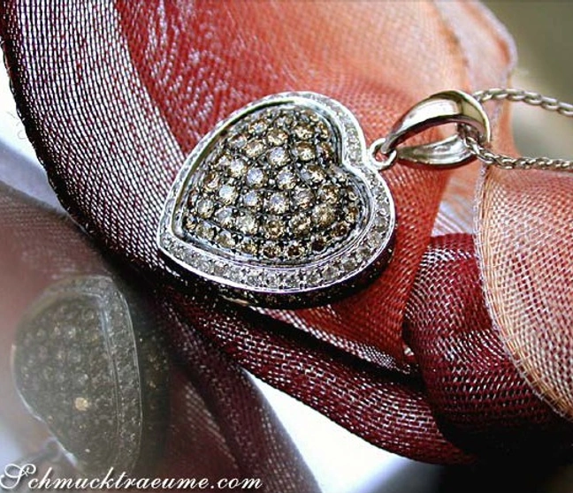 Herz-Anhänger mit braunen und weißen Brillanten, Detailaufnahme, auf rotem Stoff getragen Herz-Anhänger mit braunen und weißen Brillanten, Detailaufnahme, auf rotem Stoff getragen