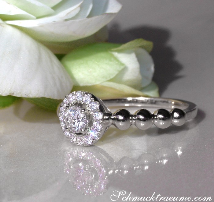 Detailaufnahme des Diamantenringes mit Kugeldesign und Rosenblüte im Hintergrund