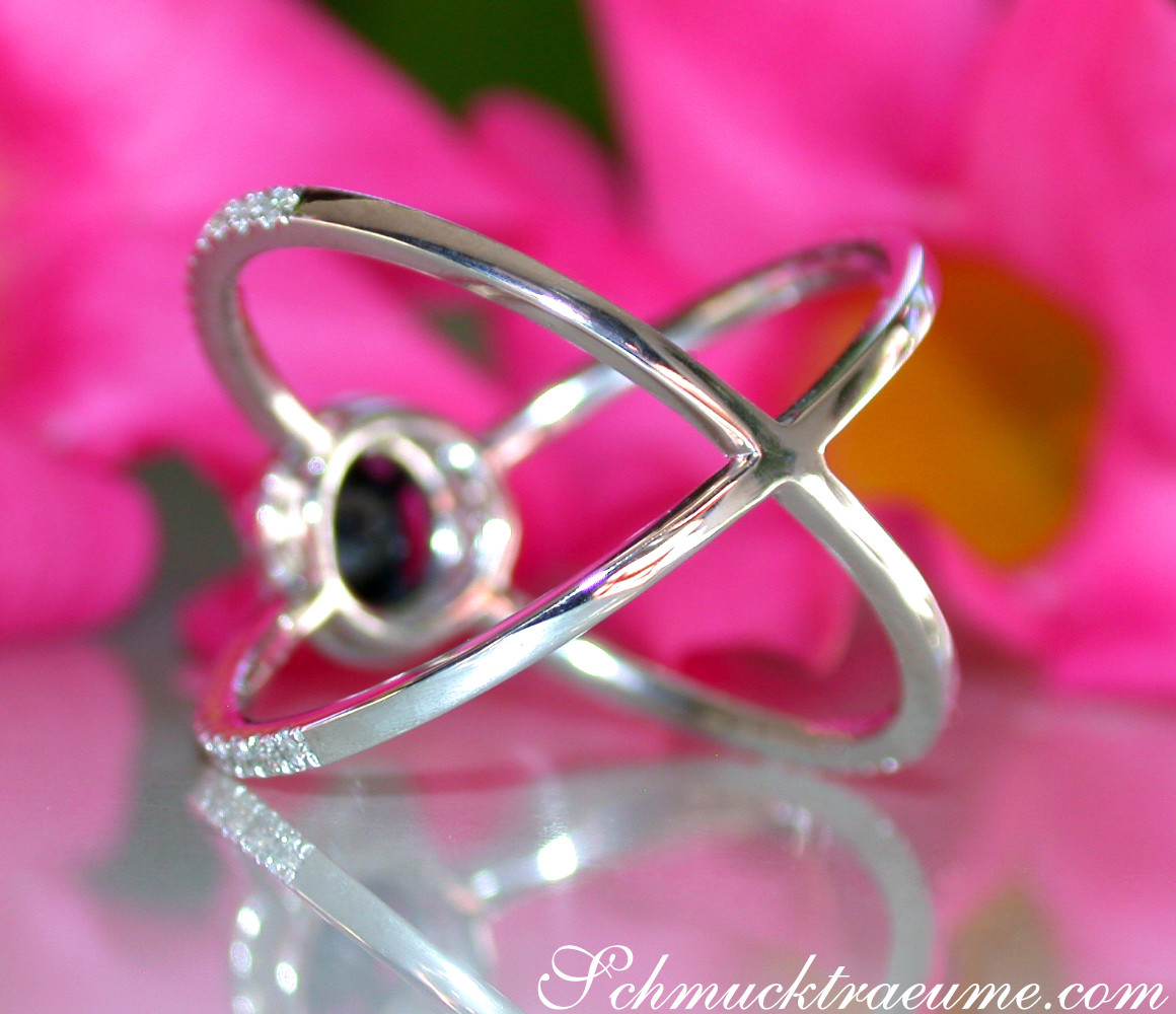 Weißgold-Ring mit überkreuztem Design und schwarzer Diamant-Solitär vor Blüte.