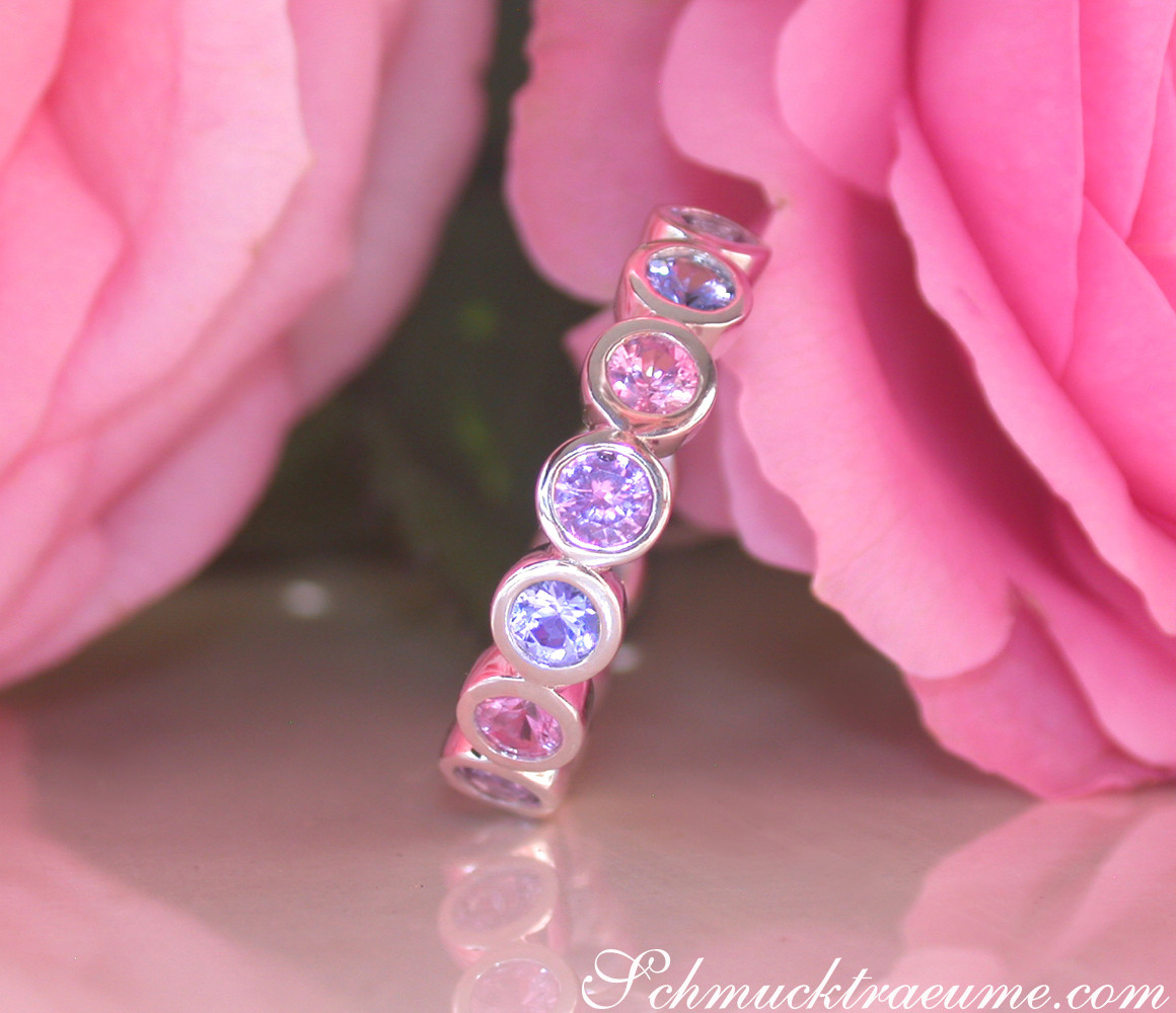 Zarte Saphirringe mit Pastelltönen vor Rosenblüten